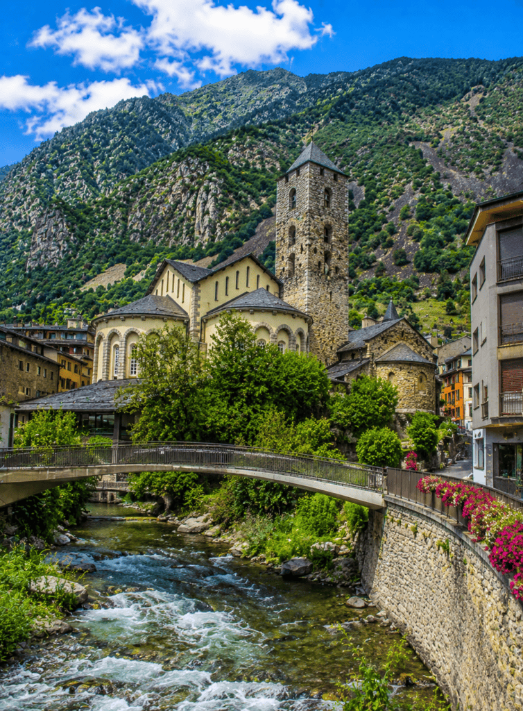Historic mountain village with church, river, and colorful buildings in the Alps.