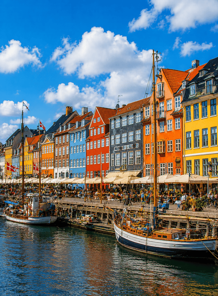 Vibrant waterfront buildings in Nyhavn, Copenhagen, with boats docked along the canal and lively out.